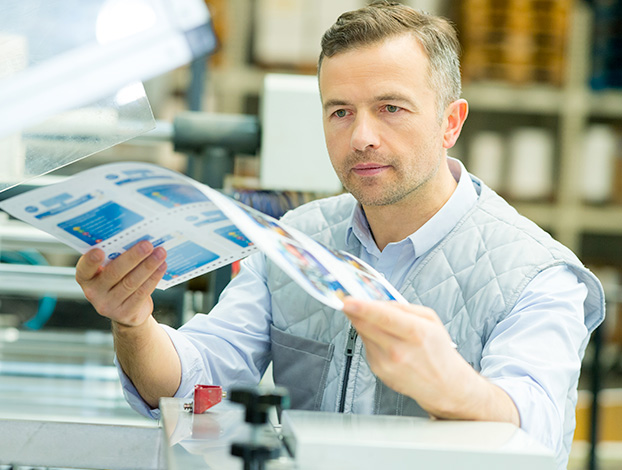 A male print inspector reviewing commercial document.