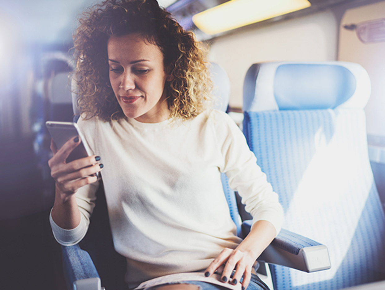 Woman sitting on a train reading checking her mobile phone 
