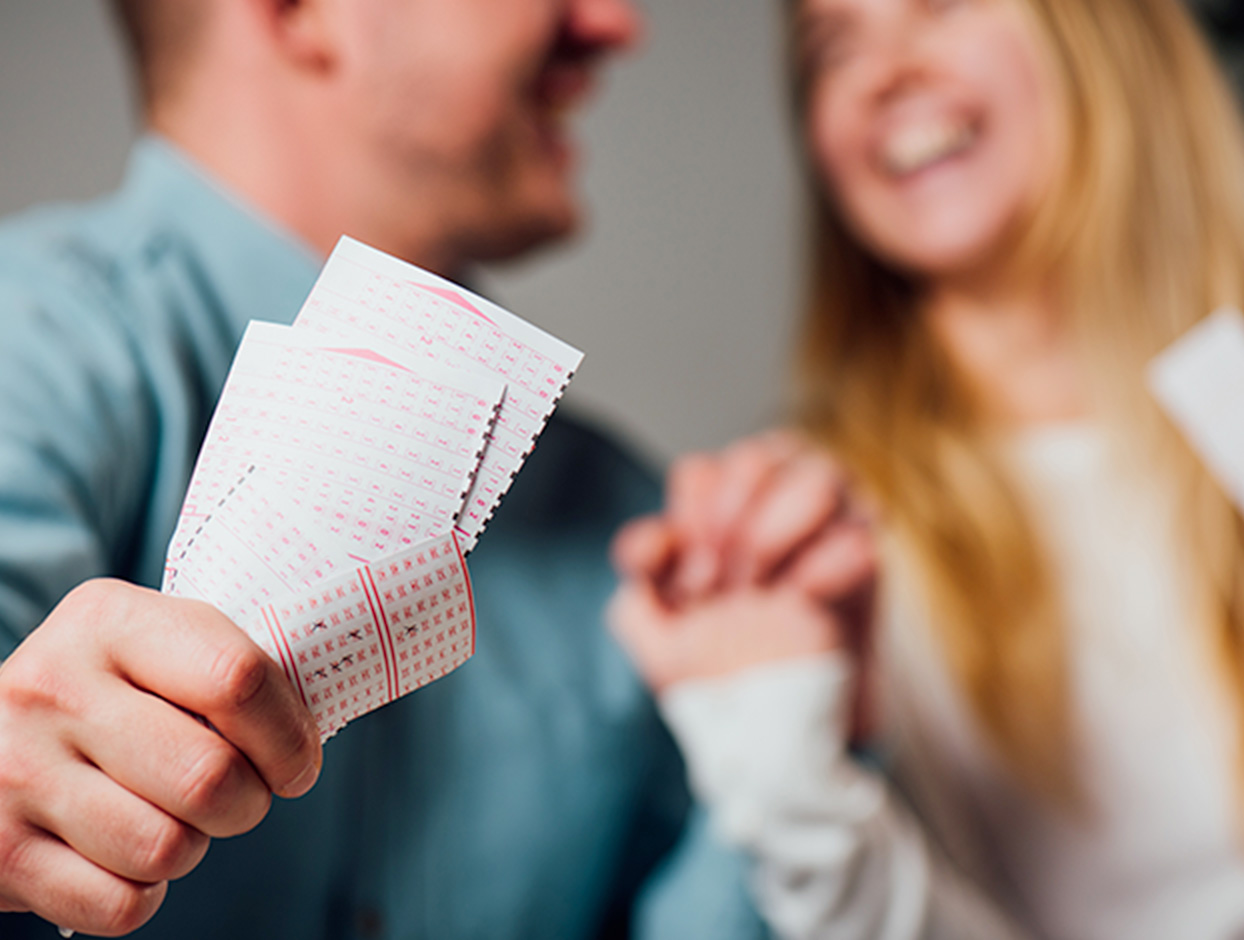 blurred out couple holding a set of lottery tickets 