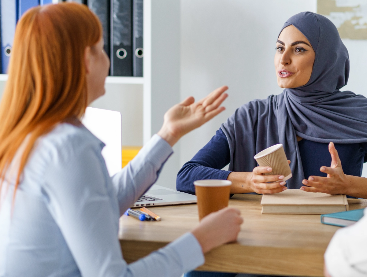 Two woman from different backgrounds talking in an office