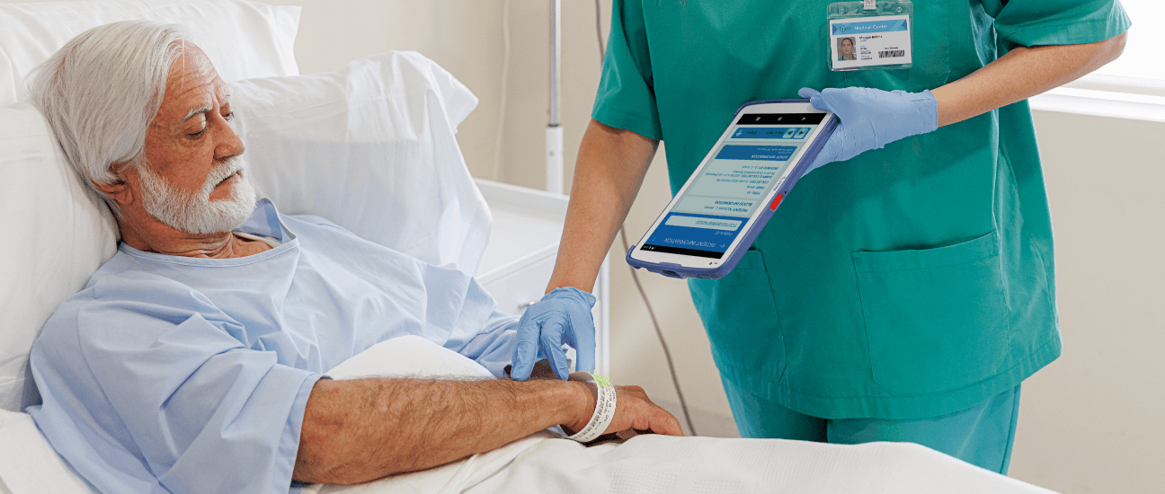 Nurse checking wrist lable on a elderly male patient with a scanner